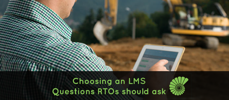 Construction worker on a worksite investigating an issue on an iPad with digger in the background text reads 'Choosing an LMS, questions RTOs should ask' with the Ammonite logo on the right hand side of the text