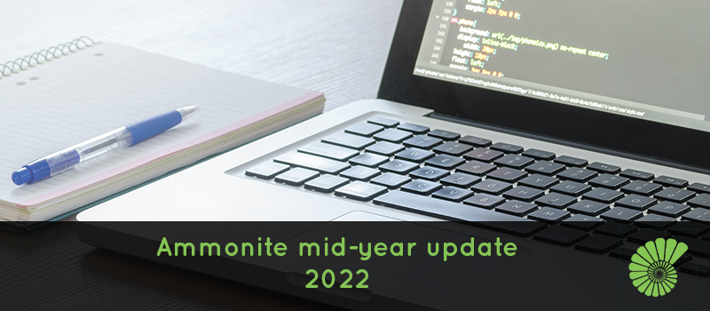 Notepad and pen with Apple laptop running code script with the text, Ammonite mid-year update 2022 with the Ammonite logo on the right