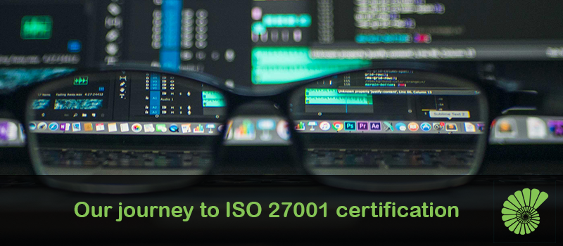 Developer's computer with glasses sitting in front showing screens and code. Caption reads "our journey to ISO 27001 certification"