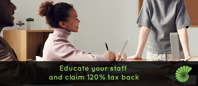 Two employees completing training in their small business text says Educate your staff and claim 120% tax back overlaying image, Ammonite logo on right hand corner